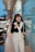 A stylish woman carrying a chic handbag while walking in a vibrant urban setting.