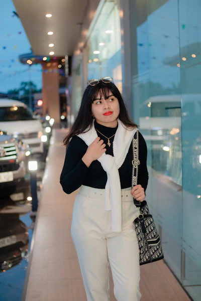 Elegant woman carrying a sleek crossbody bag while walking in a city street.