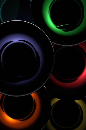 Concentric circles with vibrant neon colors create an abstract and futuristic design. The colors include deep green, blue, red, orange, and yellow, set against a dark background, enhancing the glowing effect.