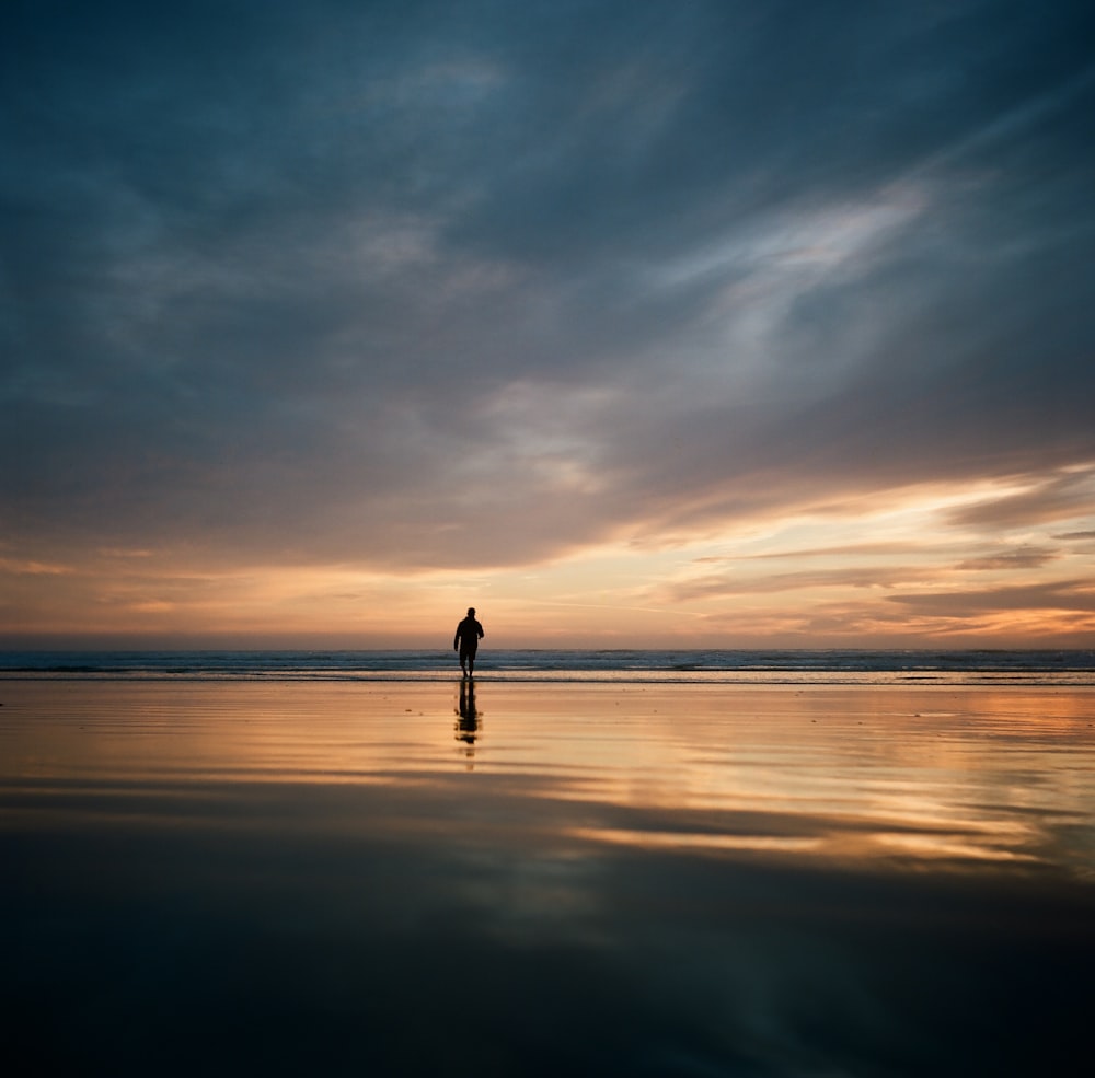 a person standing on a beach at sunset