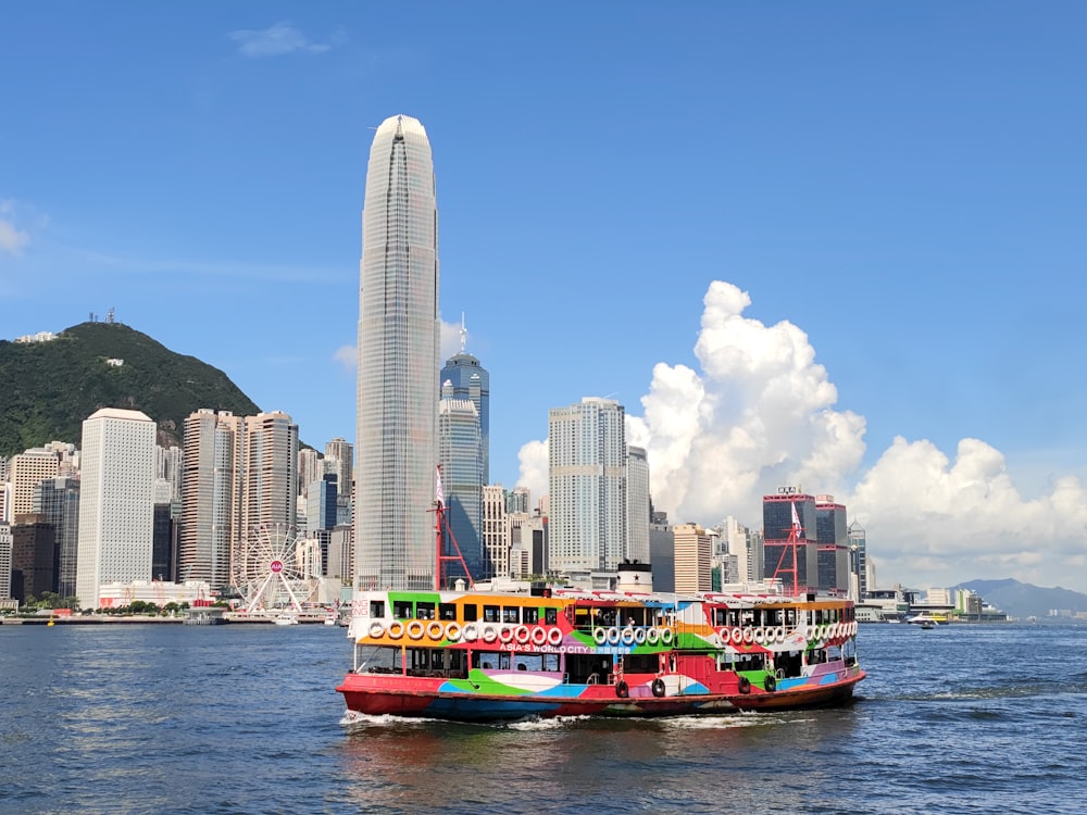 a colorful boat in a body of water with a city in the background