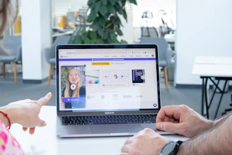 a man and a woman sitting in front of a laptop computer