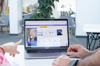 a man and a woman sitting in front of a laptop computer