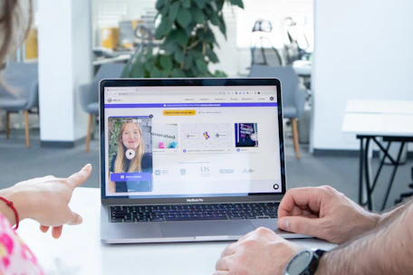 a man and a woman sitting in front of a laptop computer