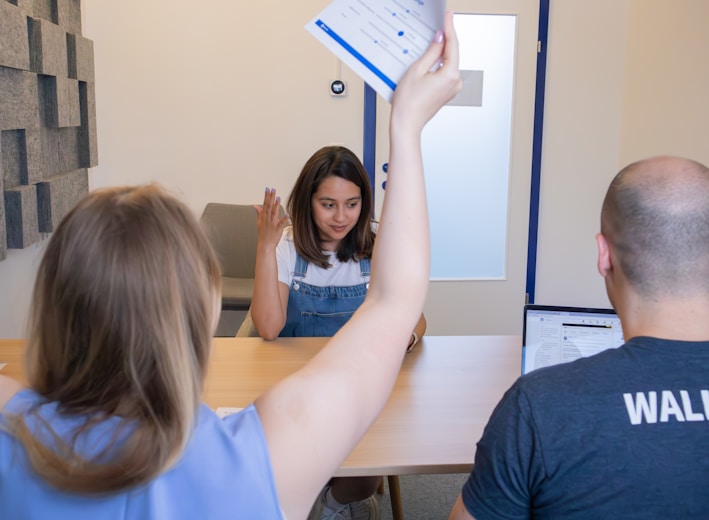 a woman holding up a piece of paper in front of a man