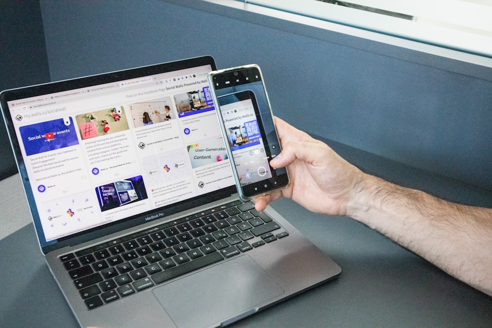 a man holding a tablet and a laptop computer