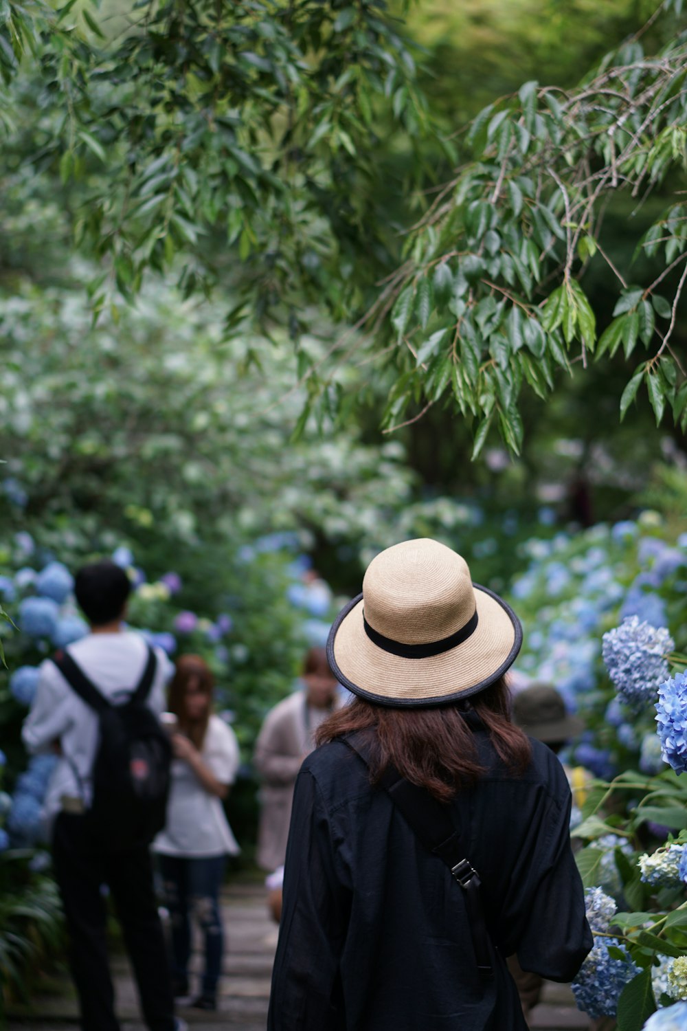 a woman wearing a hat walking down a path