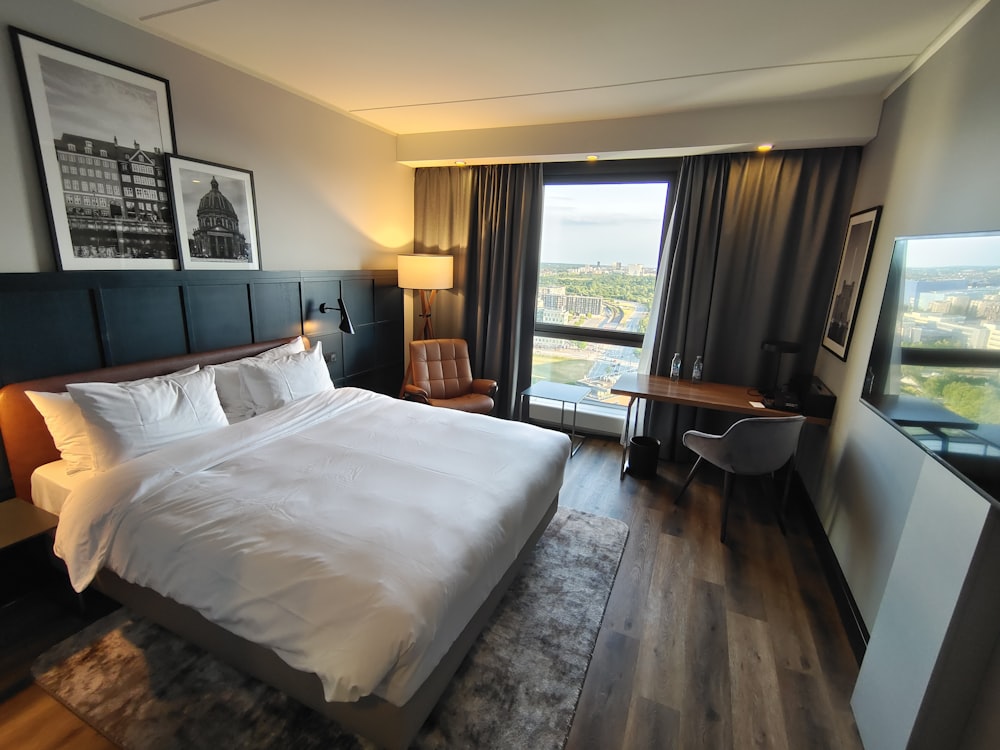 a large white bed sitting in a bedroom next to a window