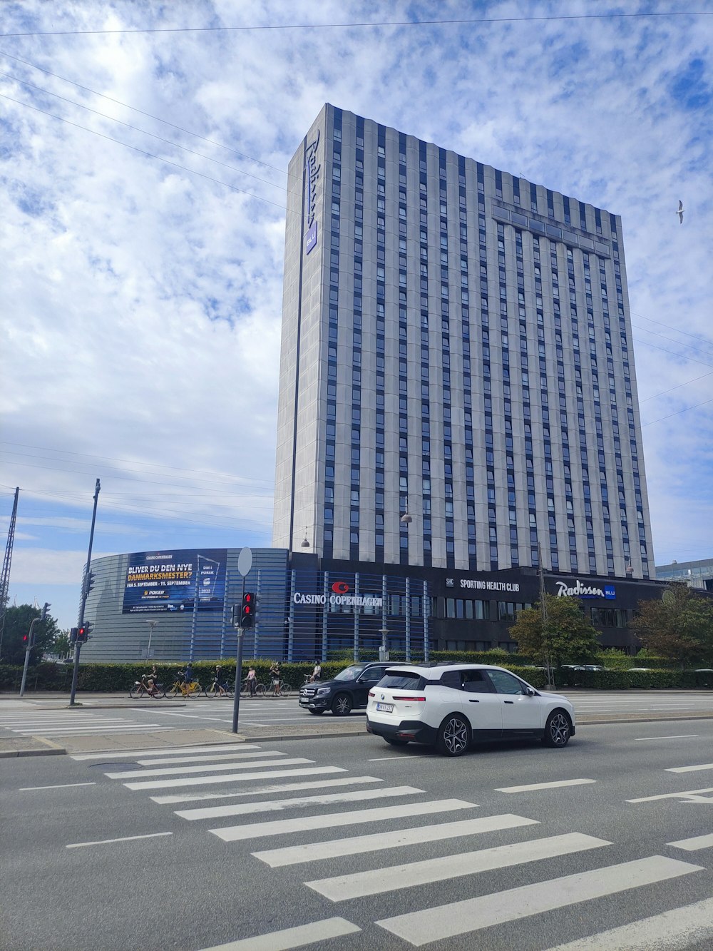 a white car driving down a street next to a tall building