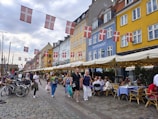 A lively New Jersey street with colorful restaurant signs and people enjoying outdoor dining.