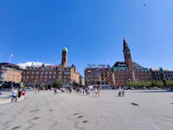 Historic city square filled with people enjoying a sunny day.