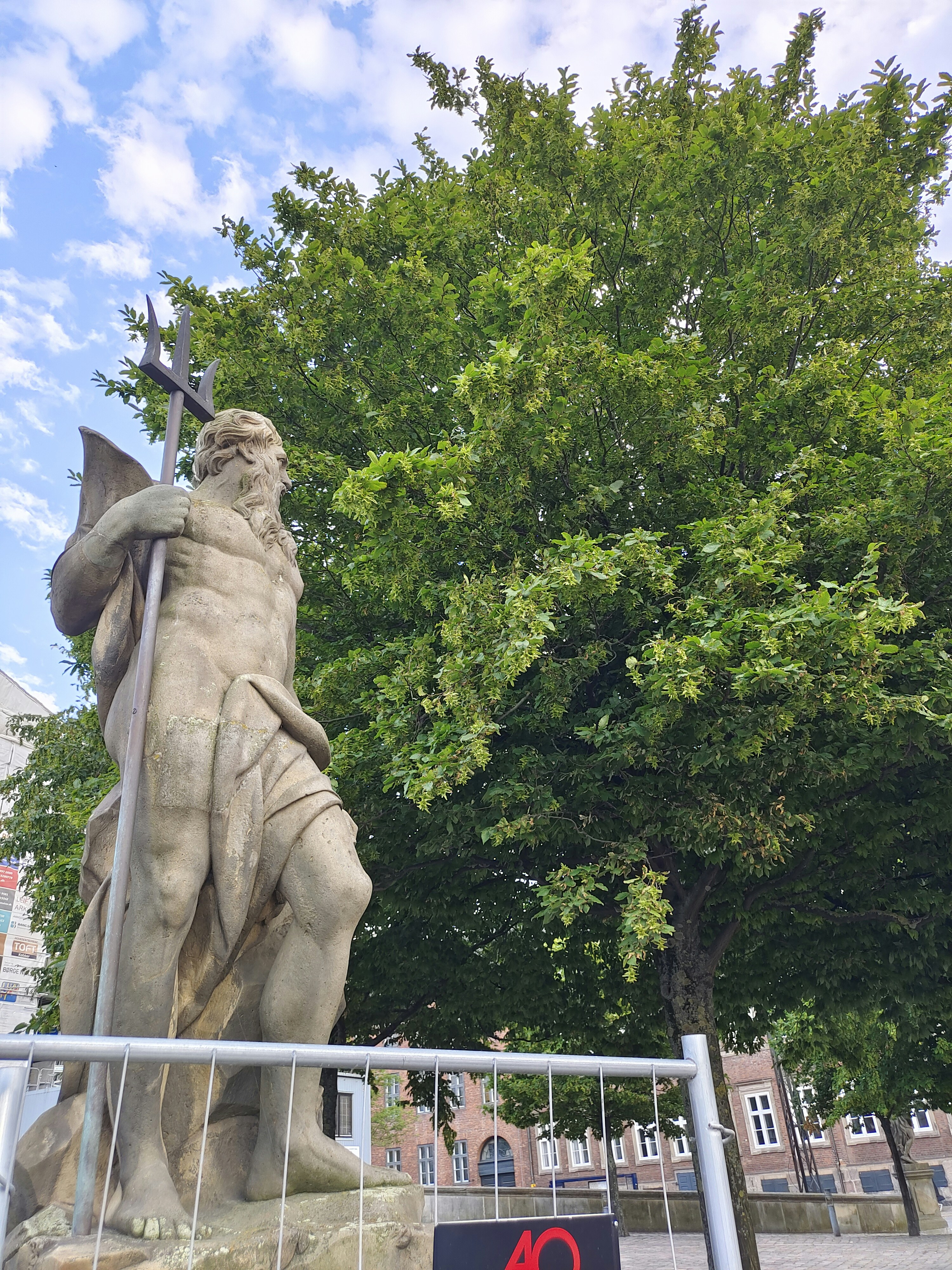 a statue of a man holding a cross next to a tree