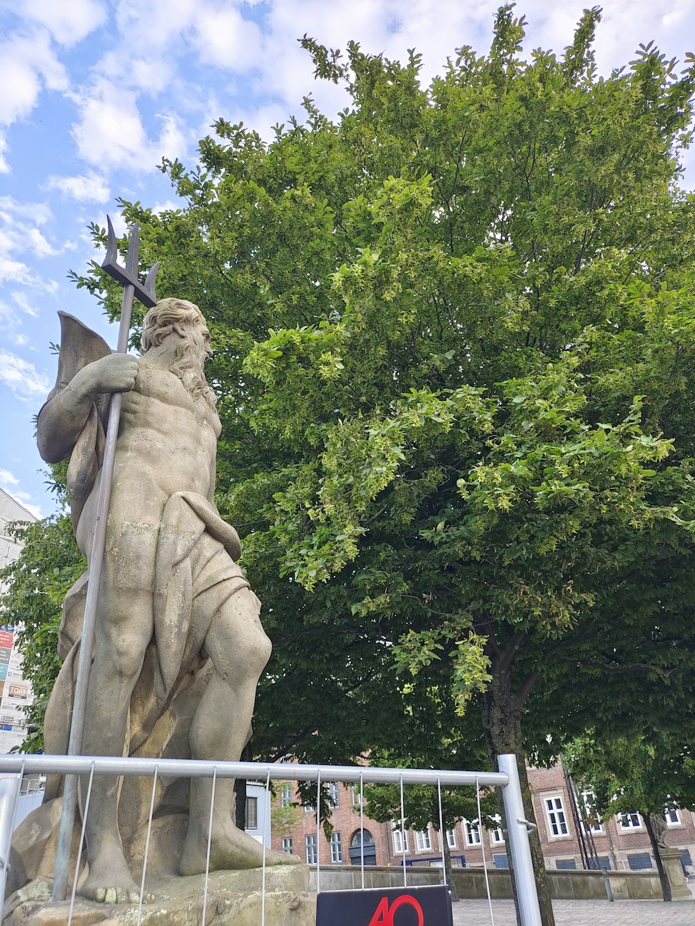 a statue of a man holding a cross next to a tree