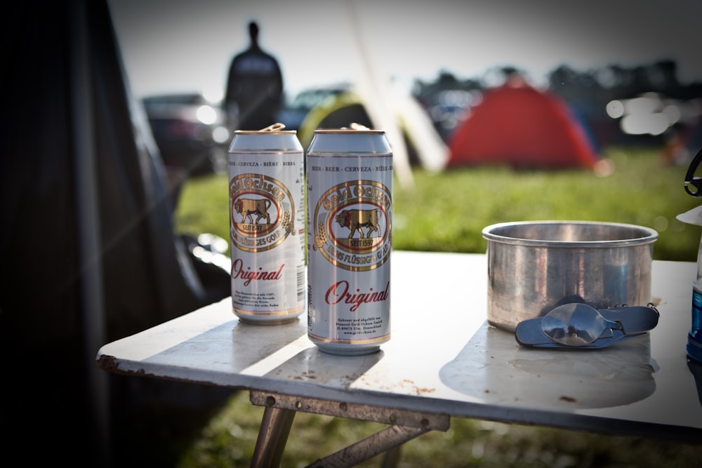 two cans of beer sitting on top of a table