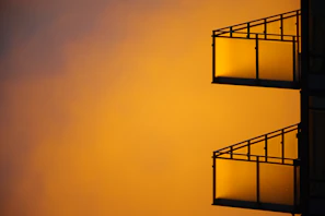 Evening shot of a balcony warmly lit behind clear glass panels.
