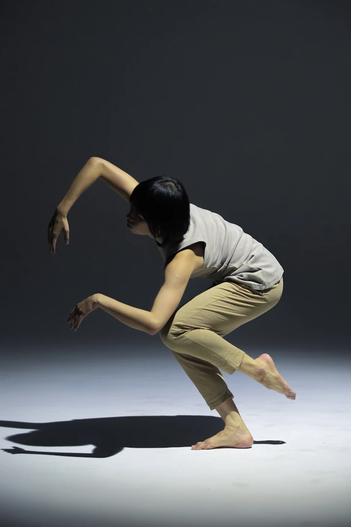 Contemporary dancer mid-movement in dim studio lighting