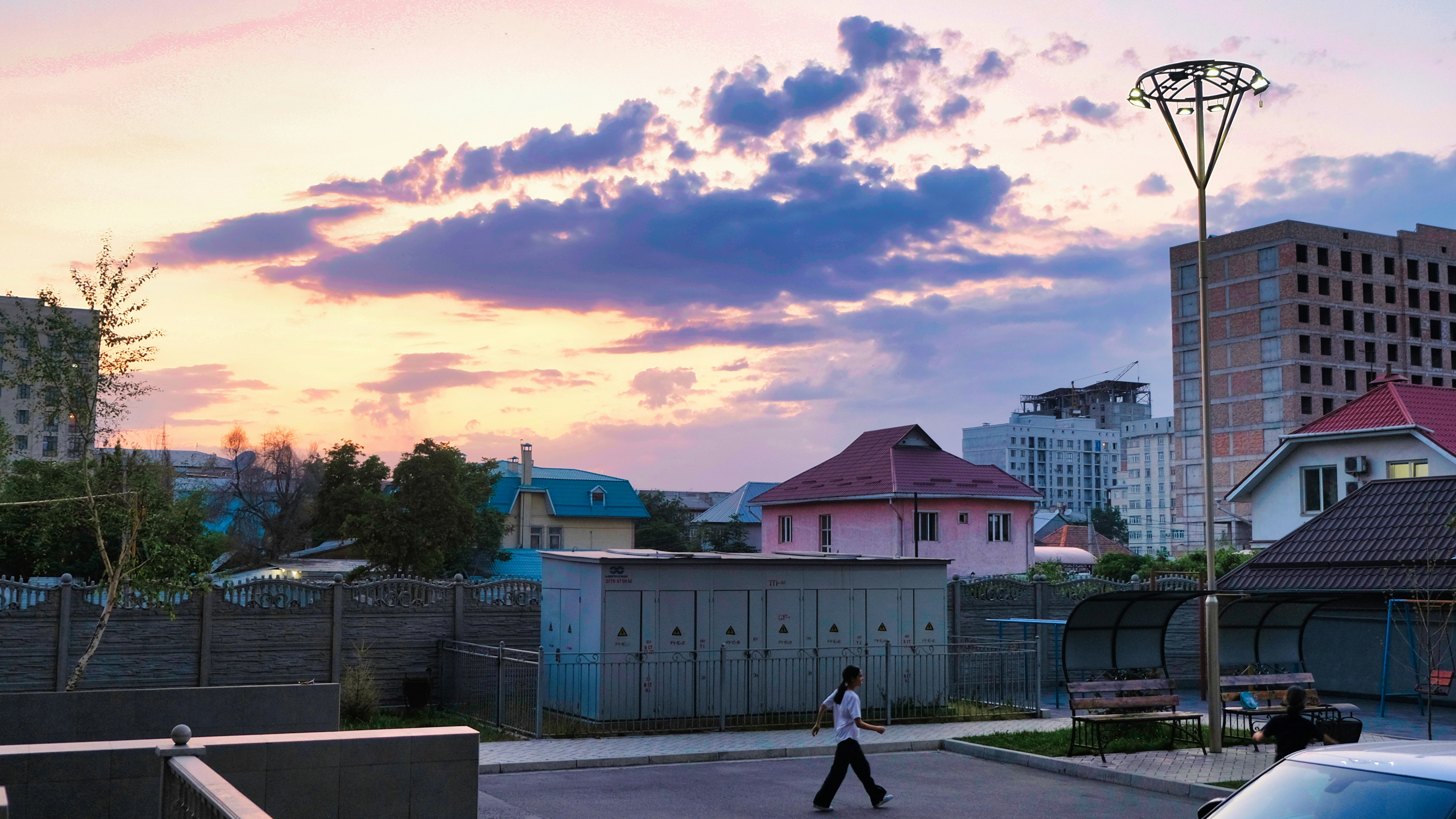 a man walking across a parking lot next to tall buildings