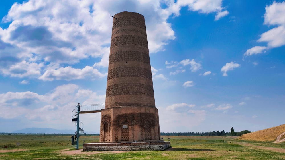 a tall brick tower sitting on top of a lush green field