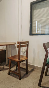 Neat non-AC room featuring a small table and chair beside the bed.