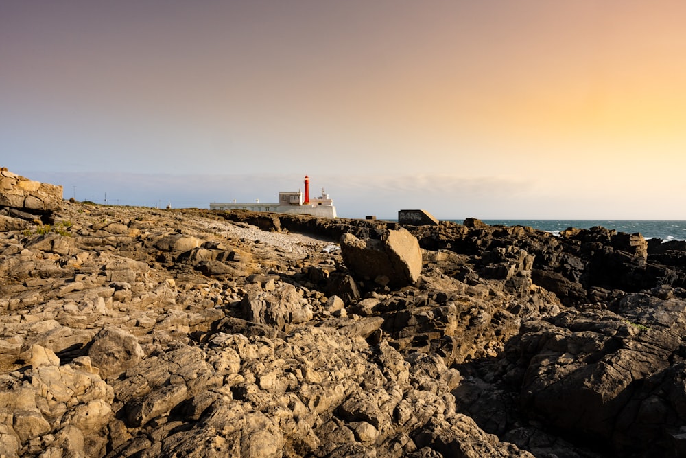 a lighthouse on a rocky shore at sunset