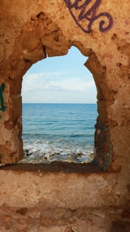 a view of the ocean through a hole in a wall