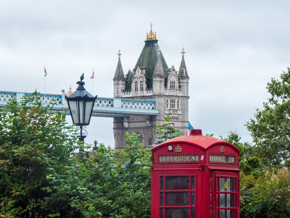 a red telephone booth in front of a bridge