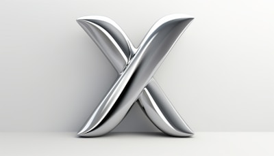 A sleek metallic X-shaped sculpture with a smooth, reflective surface set against a light gray backdrop. The curves and reflections on the sculpture suggest a modern and futuristic aesthetic.