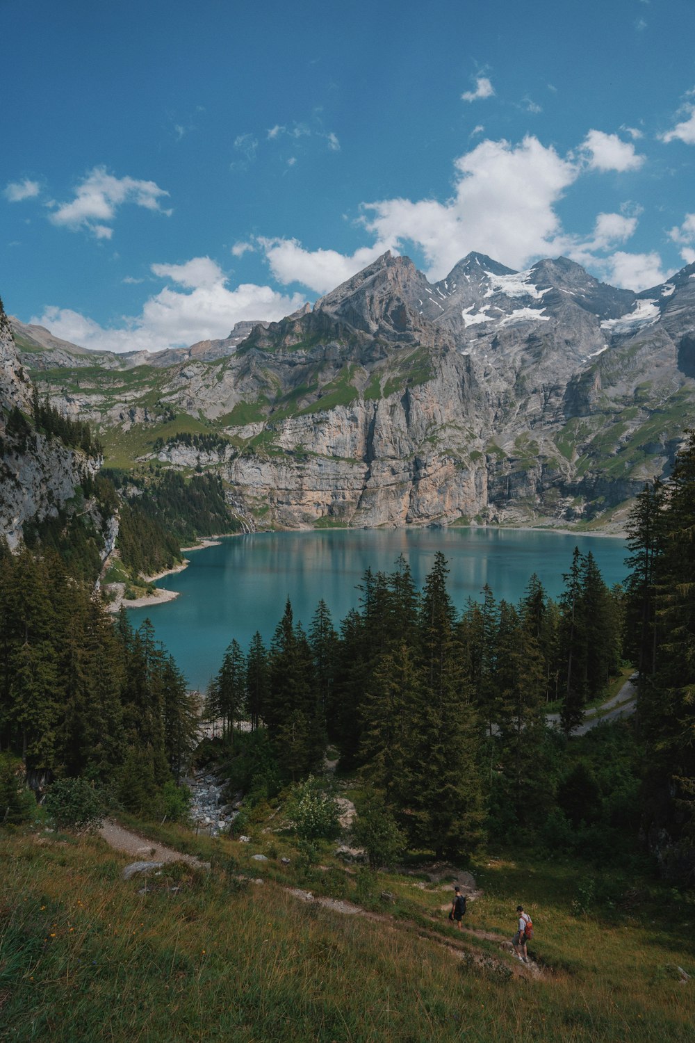 a couple of people walking up a hill next to a lake