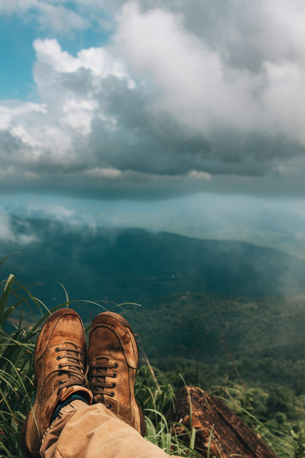 a person's feet in a pair of brown shoes on top of a mountain
