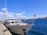 A marine surveyor examining a yacht's hull at the Port of Valencia under clear skies.