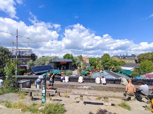 A friendly social worker speaking with diverse community members in a sunny Frankfurt park.