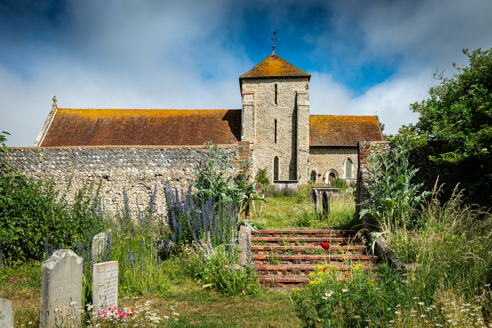 a church with a steeple surrounded by trees and flowers