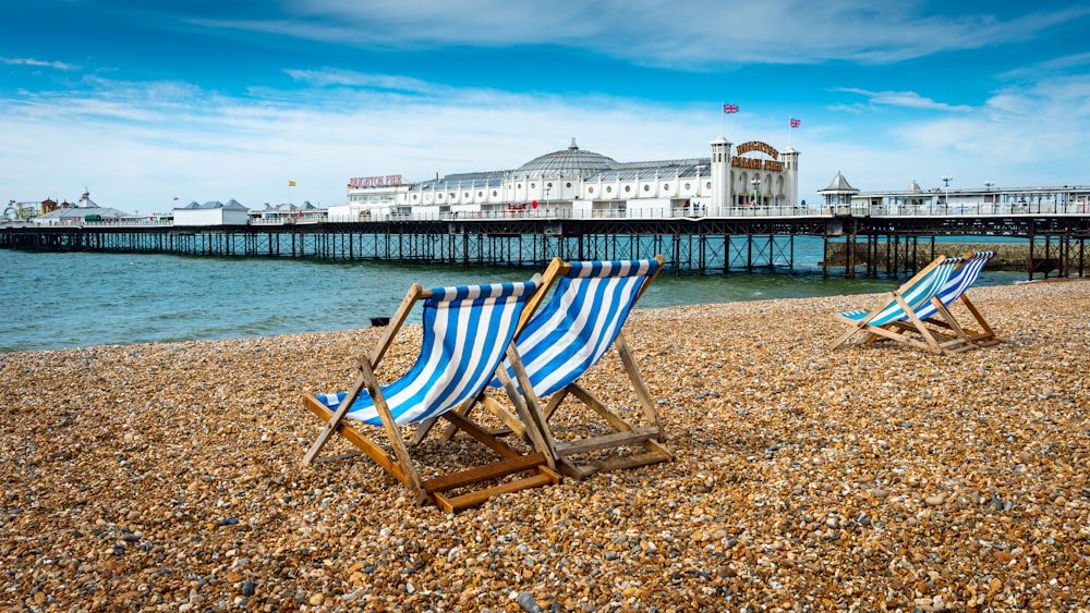 two beach chairs sitting on top of a sandy beach