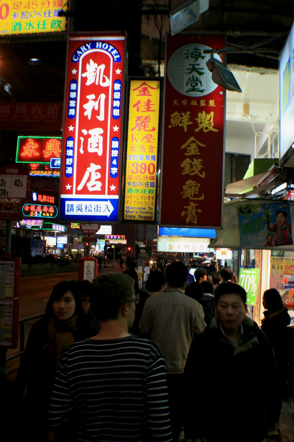 a group of people walking down a street next to tall signs