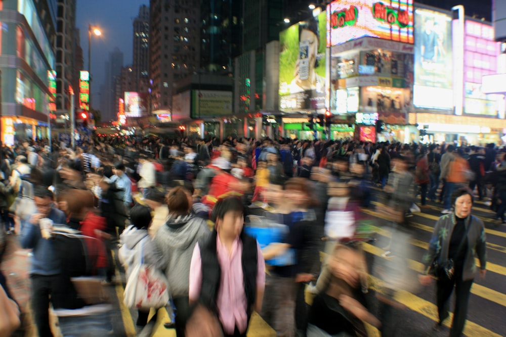 a crowd of people crossing a street at night