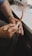 A pair of hands carefully crafts or polishes a decorative pipe. The pipe has intricate carvings and a curved, slender mouthpiece. The hands appear to be skillful, and there is a sense of precision in the work.
