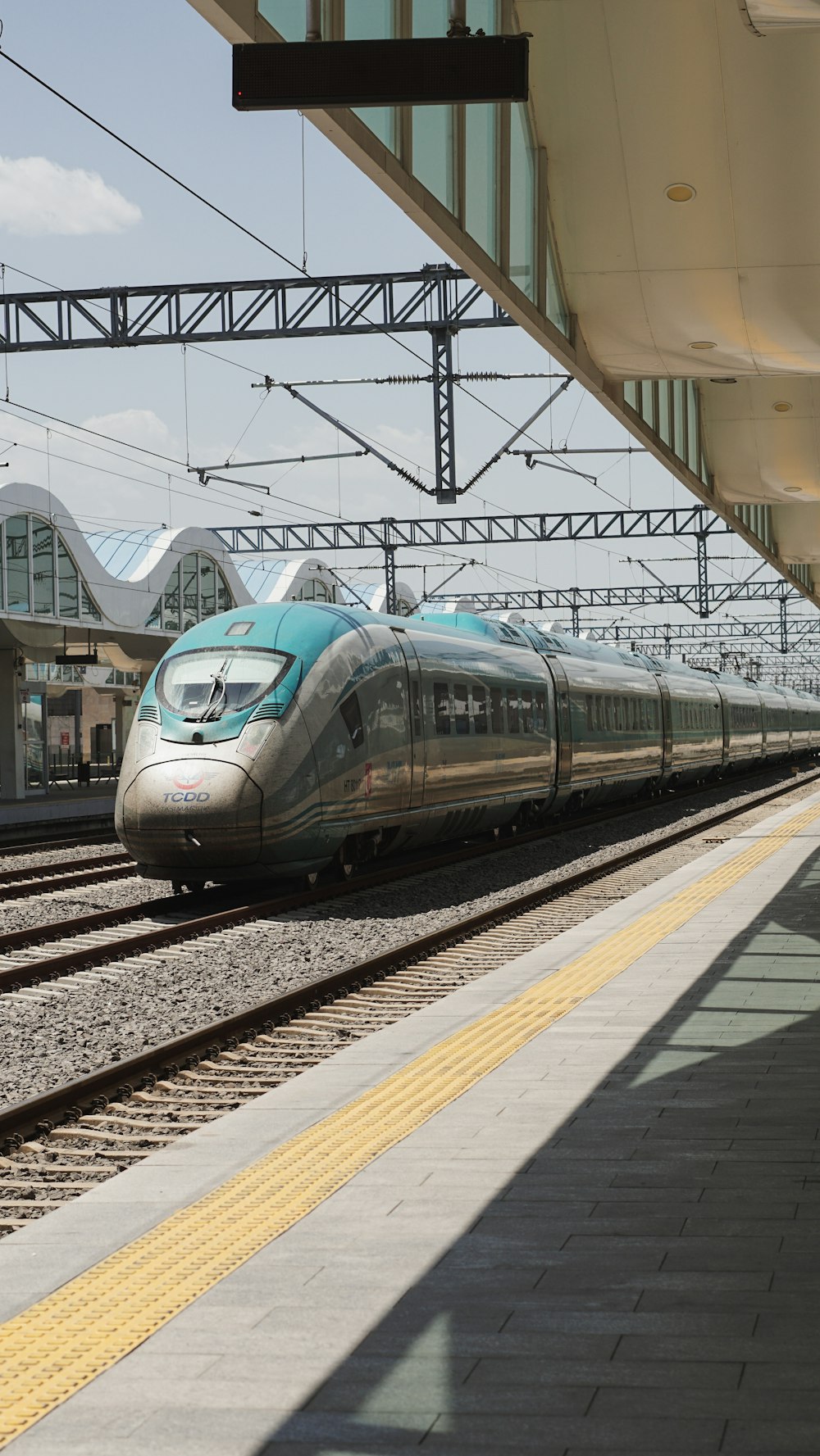 a silver train traveling down train tracks next to a train station