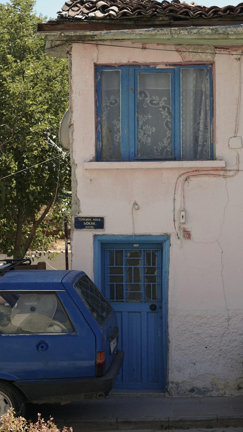 Um carro azul estacionado em frente a uma casa branca