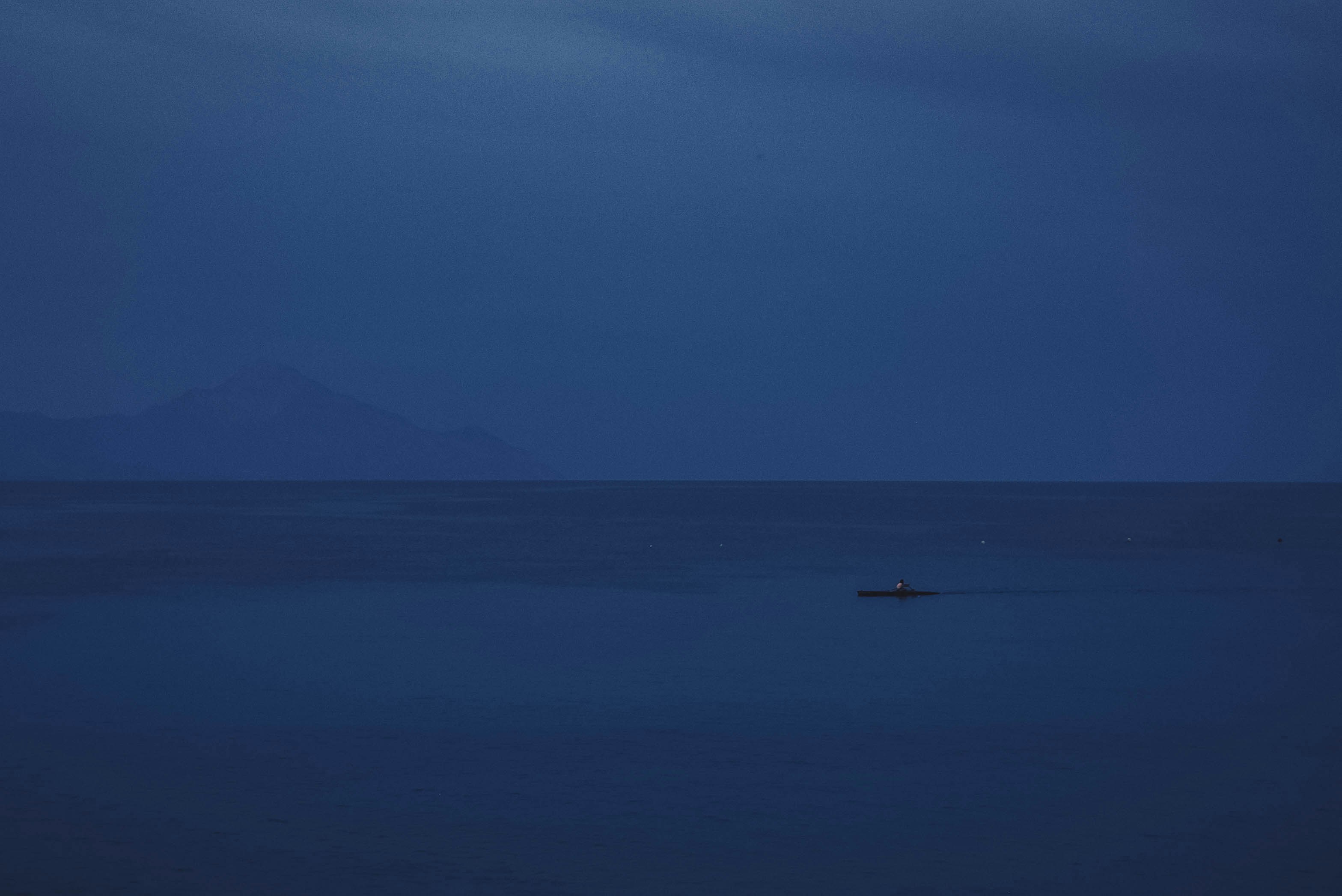 a lone boat in the middle of the ocean at night