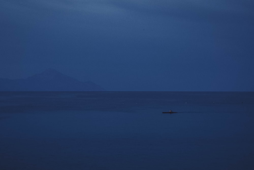 a lone boat in the middle of the ocean at night