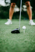 A close-up of a golfer’s swing with the clubhouse softly blurred in the background.