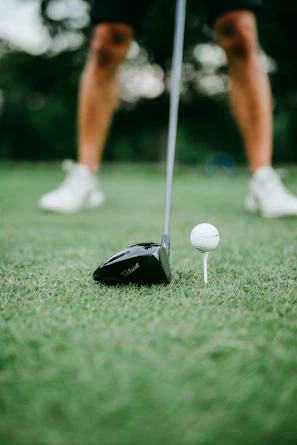 A close-up of a golfer’s swing with the clubhouse softly blurred in the background.