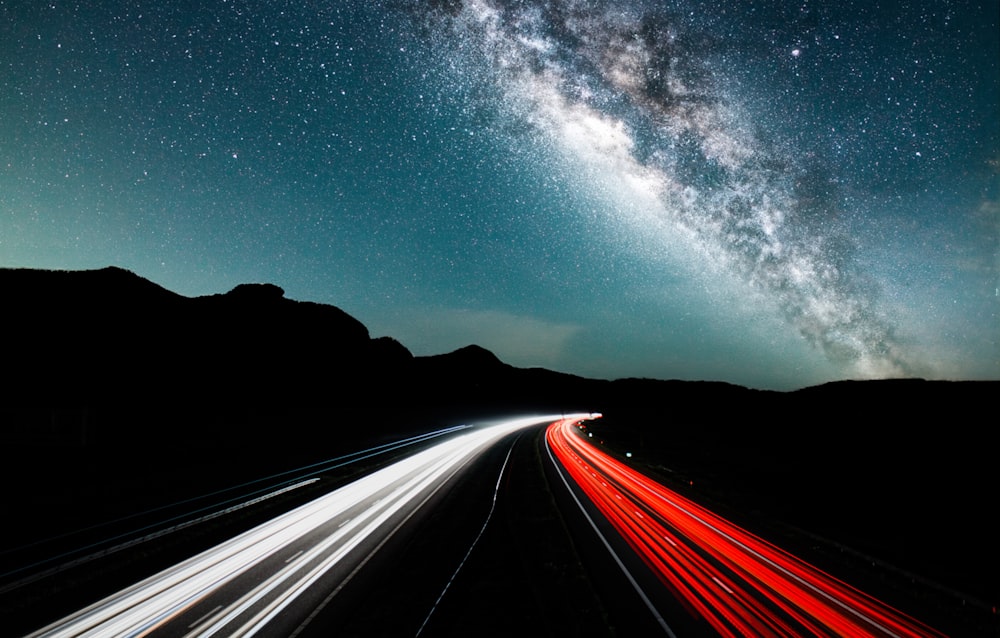 a long exposure shot of a highway at night with the milky in the background