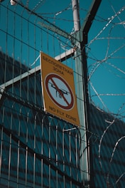 a no fly zone sign hanging on a fence