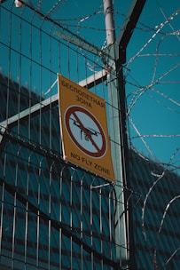 a no fly zone sign hanging on a fence