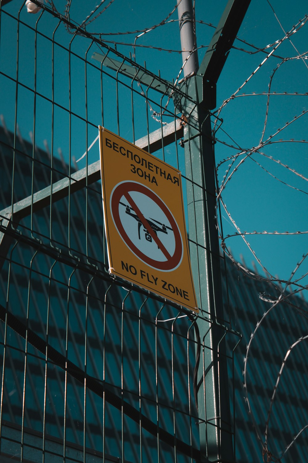 a no fly zone sign hanging on a fence