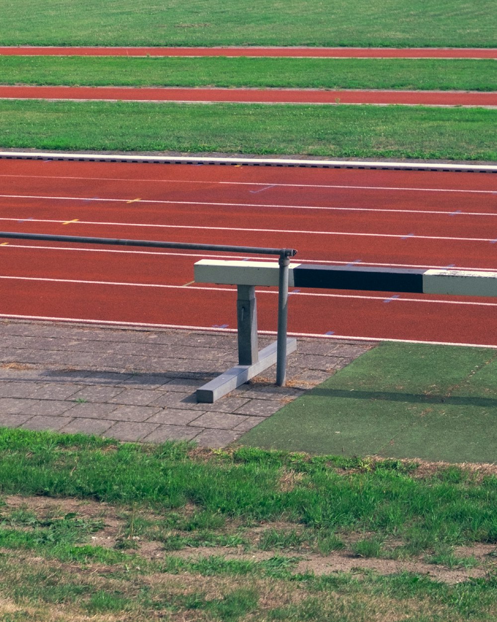 a bench sitting on top of a track next to a field