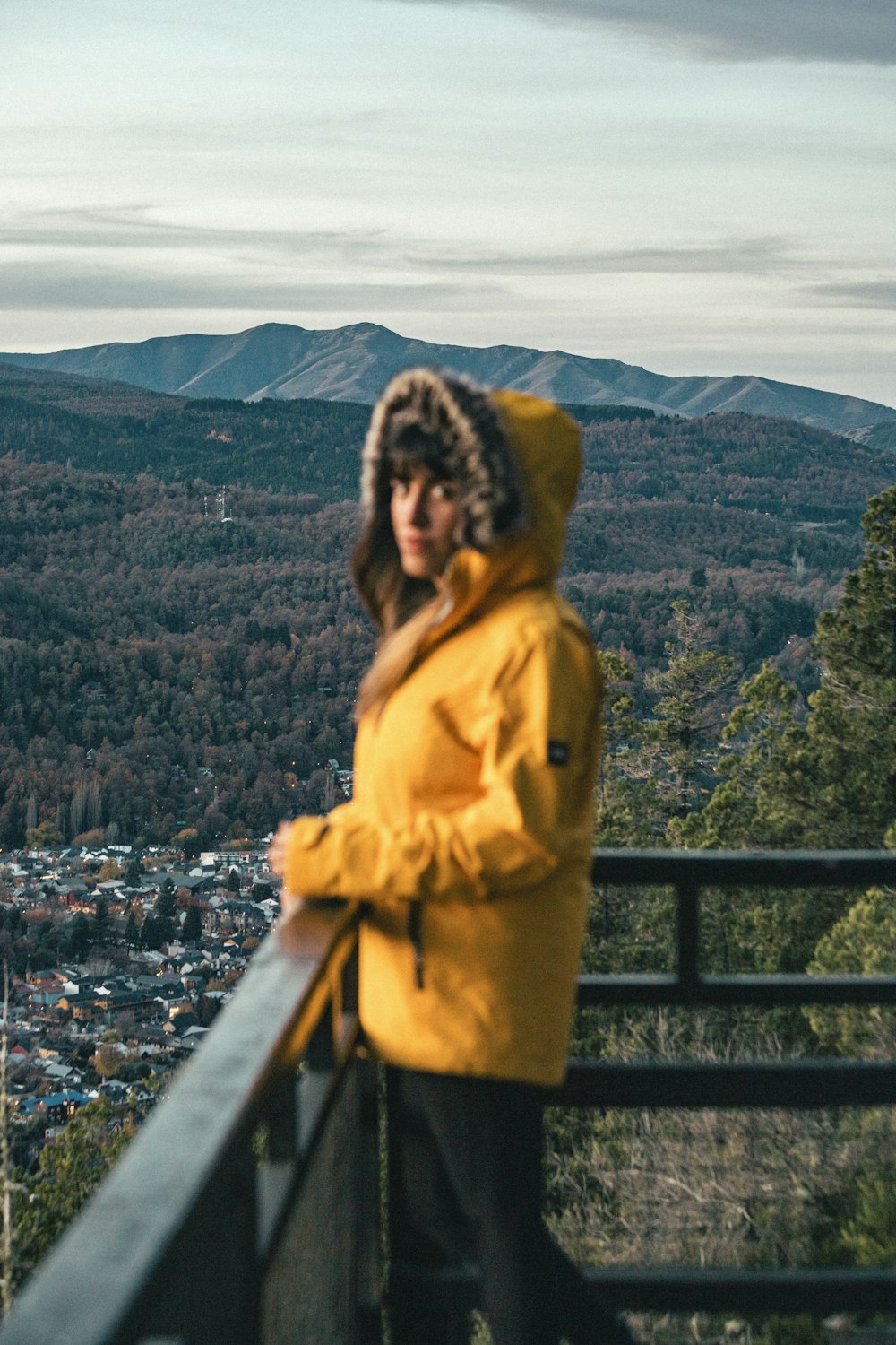 a woman in a yellow jacket standing on a balcony