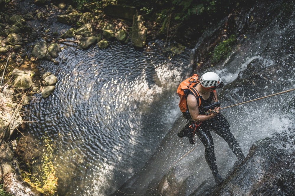 a man in a helmet is rapping a waterfall