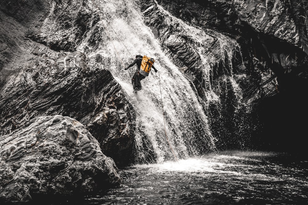 a man climbing up a waterfall in the mountains